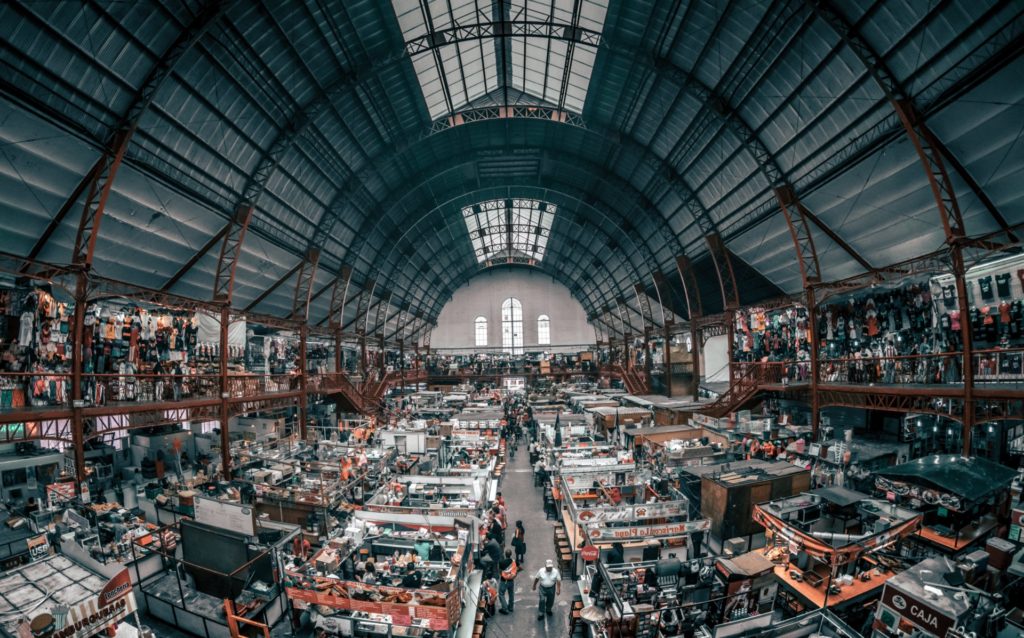 Photograph overlooking a huge vendor hall inside of a building showing lots of open booths and people walking around