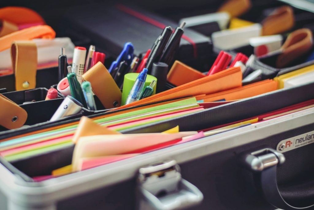 A photograph of many different office supplies in an open briefcase. 